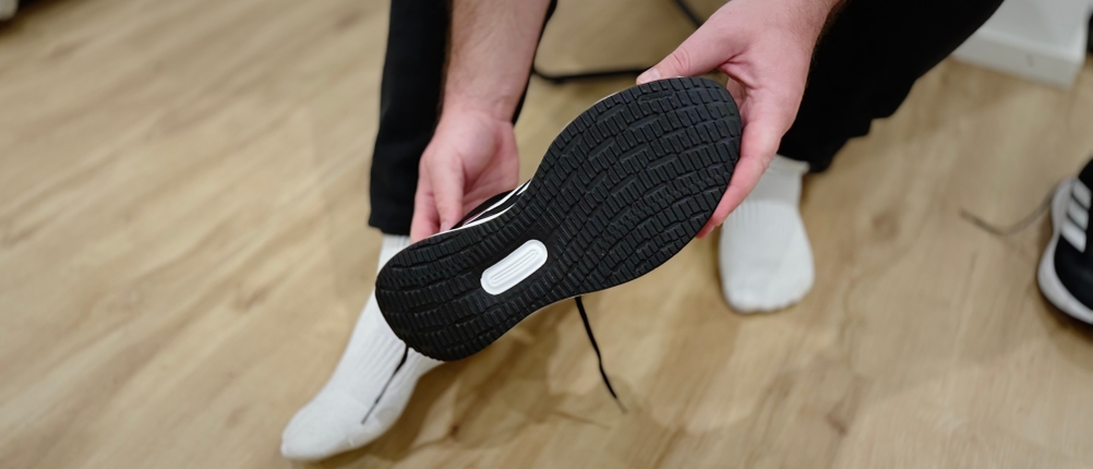 Eine Person hält einen Adidas Runfalcon 5 Laufschuh in den Händen und zeigt die Form der schwarzen Sohle.