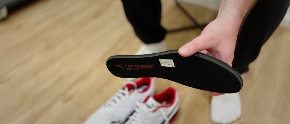 Eine Person hält eine schwarze Softfoam-Einlegesohle mit aufgedrucktem Puma-Logo in der Hand.