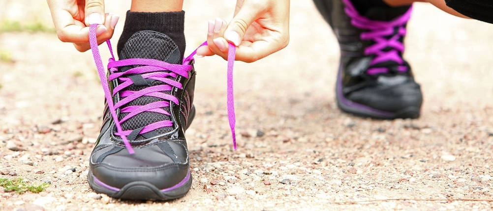 Laufsocken im Praxis-Test: Person schnürt sich die Laufschuhe mit rosafarbenen Schnürsenkeln
