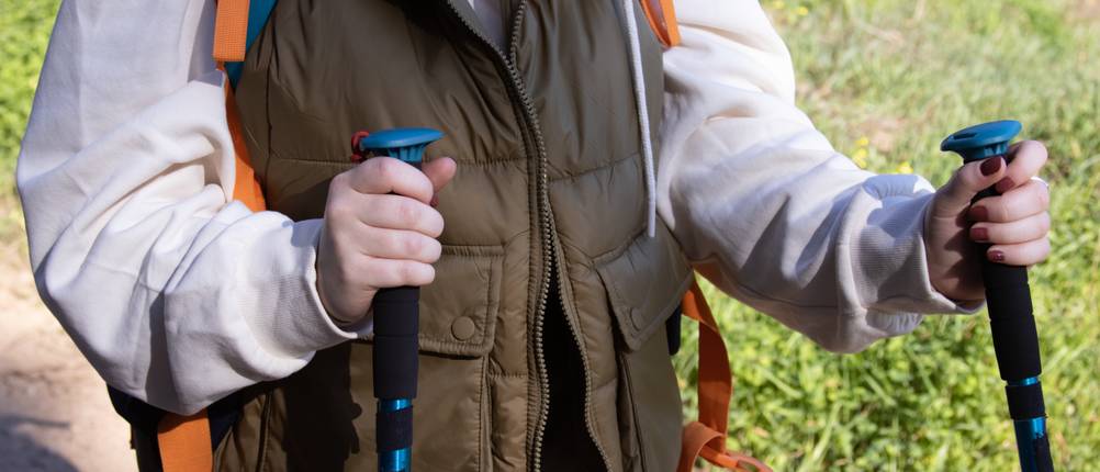 Laufweste für Herren im Test: Nahaufnahme des Oberkörpers einer Person mit Laufweste, die Nordic Walking in der freien Natur betreibt