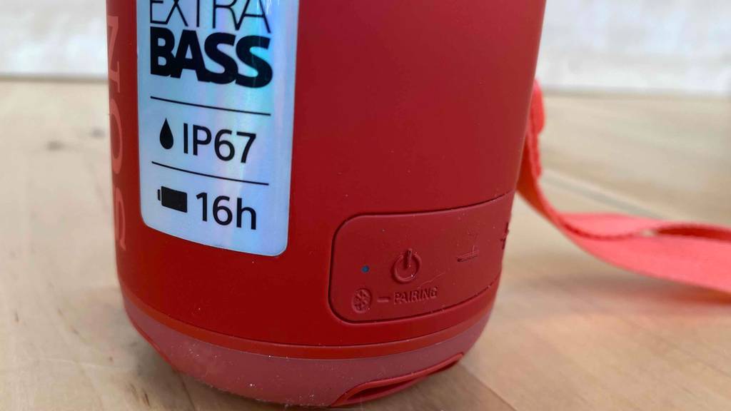 Lautsprecher im Test: mobiler Sony-Lautsprecher steht auf einem Laminatboden und zeigt ein Schild mit technischen Angaben sowie den Einschalter und die Lautstärkeregelung.