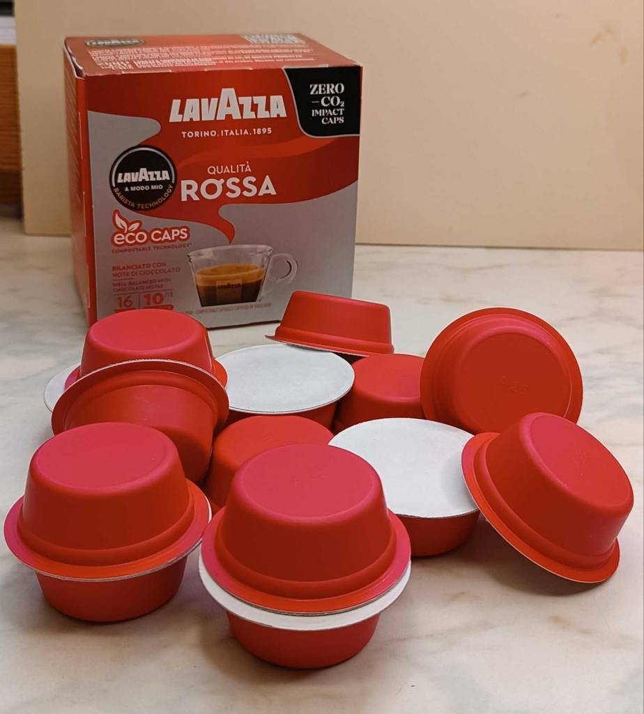 Mehrere getestete Kaffeekapseln liegen vor ihrer Originalverpackung auf einer Marmoroberfläche.