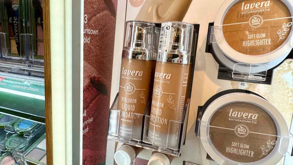 Mehrere Flaschen des Lavera-Make-up im Test auf einem Aufsteller in einem Laden.