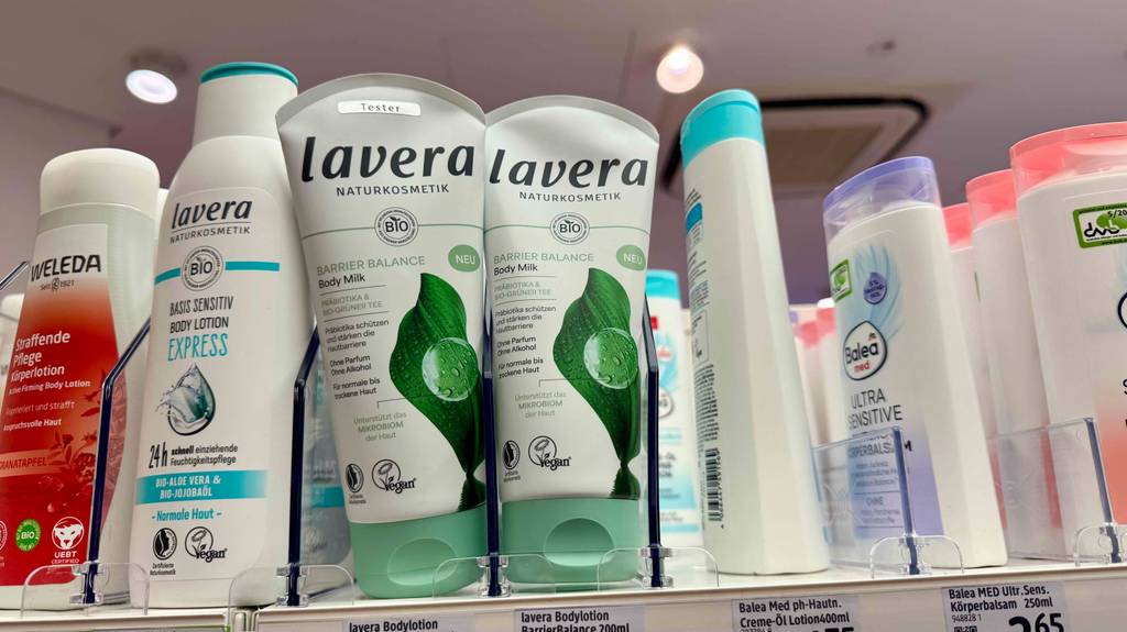Naturkosmetik-Bodylotion im Test: Mehrere Tuben stehen in zwei Reihen zwischen anderen Pflegeprodukten.