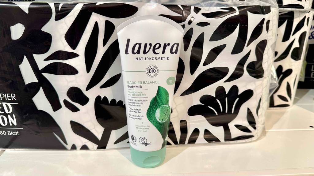 Eine Tube Naturkosmetik-Bodylotion steht zum testen vor einem schwarz-weißen Blumendesign.