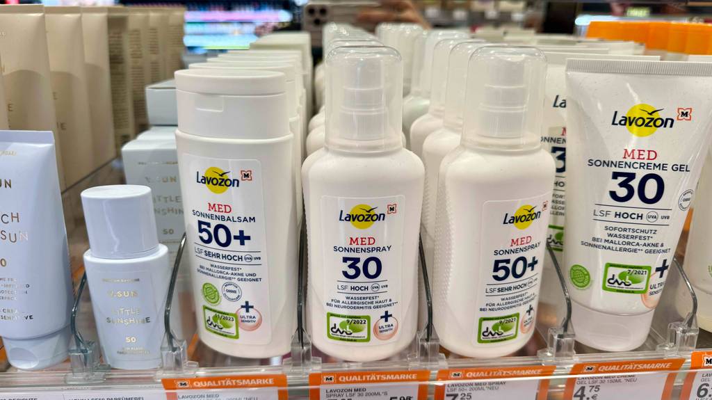 Sonnenspray im Test: Mehrere Flaschen unterschiedlicher Varianten stehen neben- und hintereinander in einem Regal.