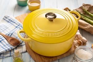Le-Creuset-Bräter-Test: Ein runder, gelber Bräter auf einem Küchenbrett mit anderen Küchenutensilien