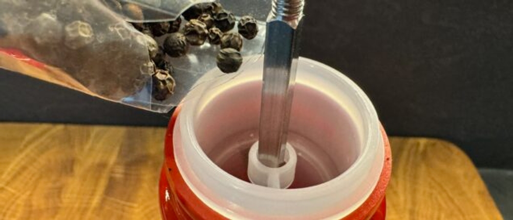 Pfefferkörner in die Le-Creuset-Salz- und Pfeffermühle einfüllen