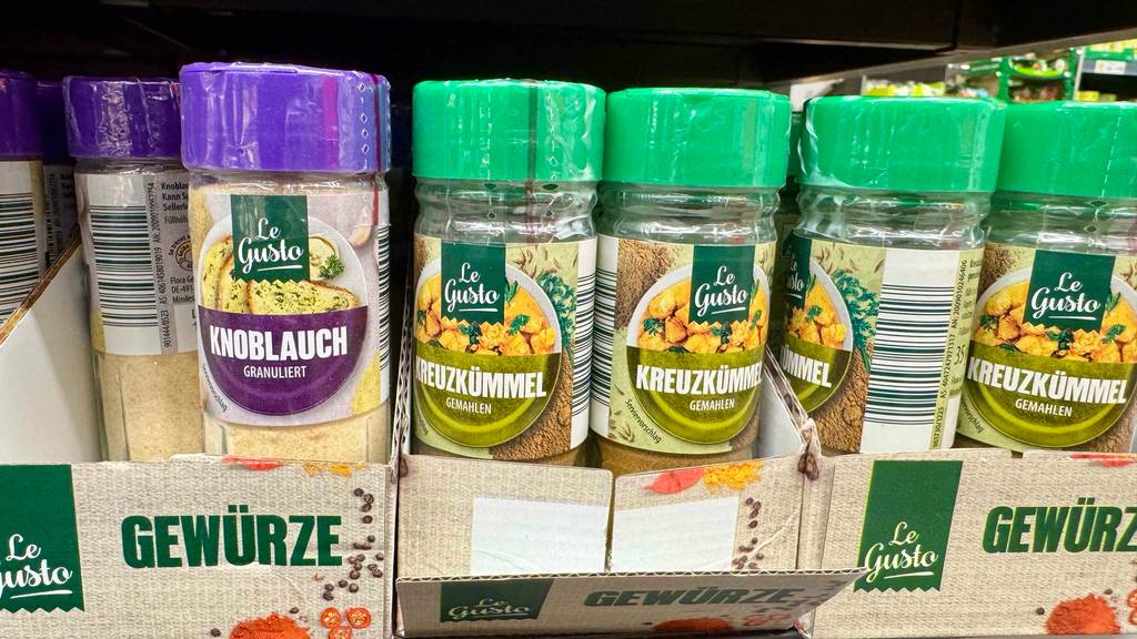 Mehrere Gewürzdosen mit Kreuzkümmel im Test stehen neben weiteren Kräuterdosen im Regal.