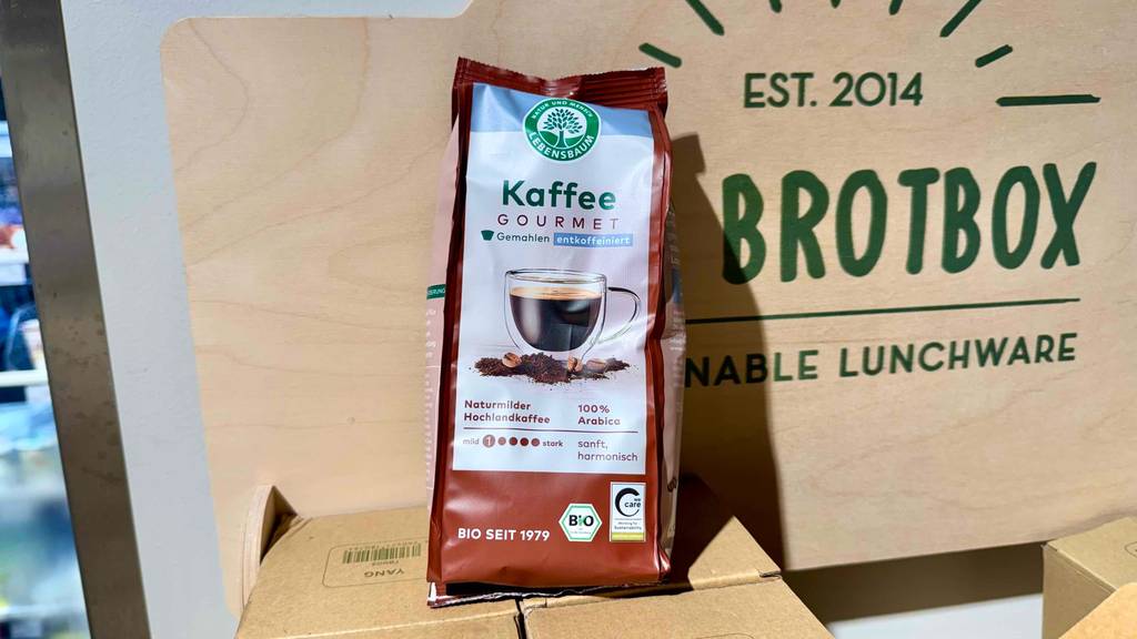 Eine Packung getesteter Lebensbaum-Kaffee lehnt an ein Plakat.