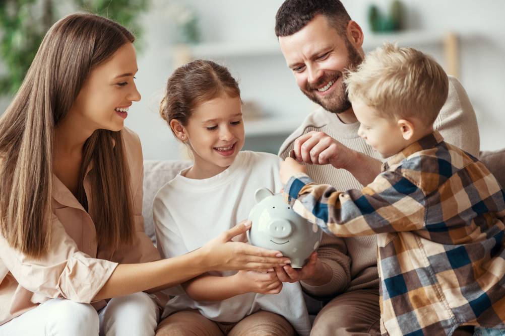 Eine Familie steckt Geld in ein Sparschwein.