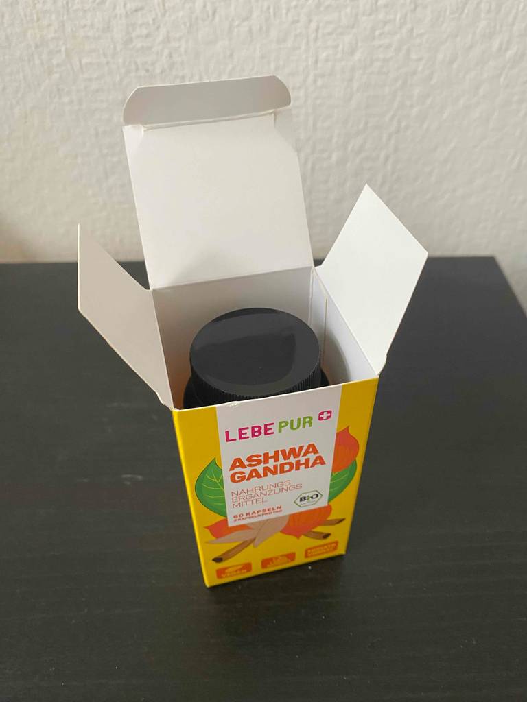 Blick von oben auf ein Fläschchen Bio-Ashwagandha-Kapseln, das zum testen in der geöffneten Verpackung steht.