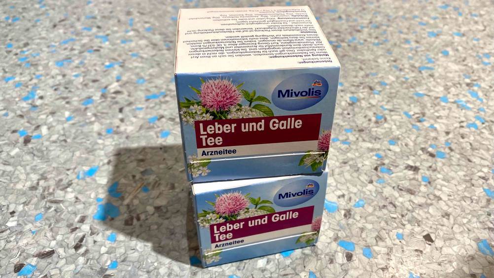 Zwei Packungen des getesteten Lebertees übereinander auf einem grauen Boden.