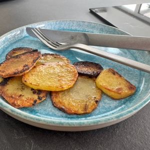 Fertige Bratkartoffeln auf einem Teller mit Messer und Gabel