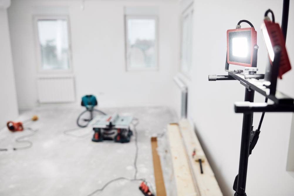 Led-Baustrahler-mit-Stativ im Test: eine verschwommen zu sehende Baustelle mit einem Strahler im Anschnitt rechts.