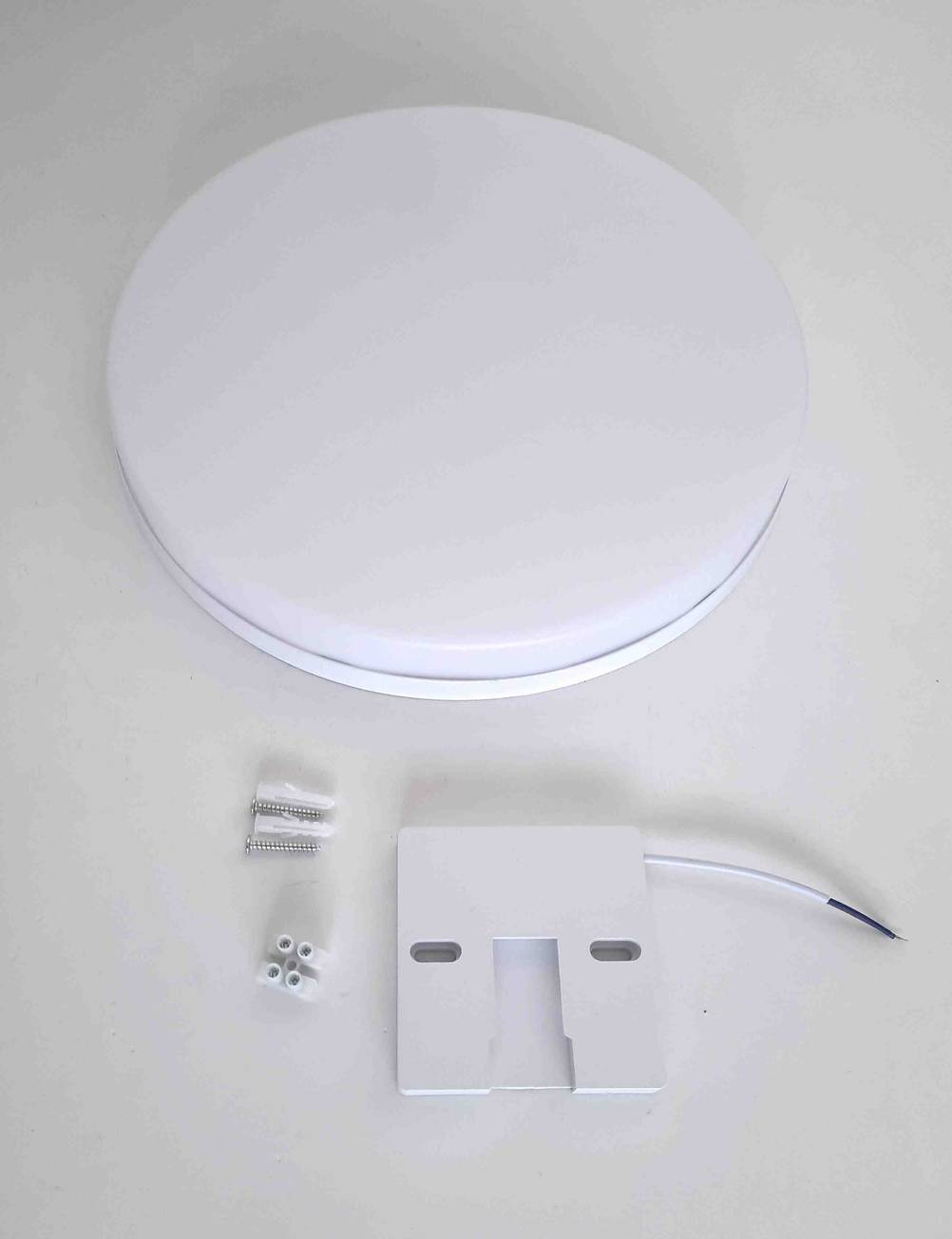 Eine LED-Deckenleuchte im Test inklusive Zubehörteilen auf einer hellen Fläche.