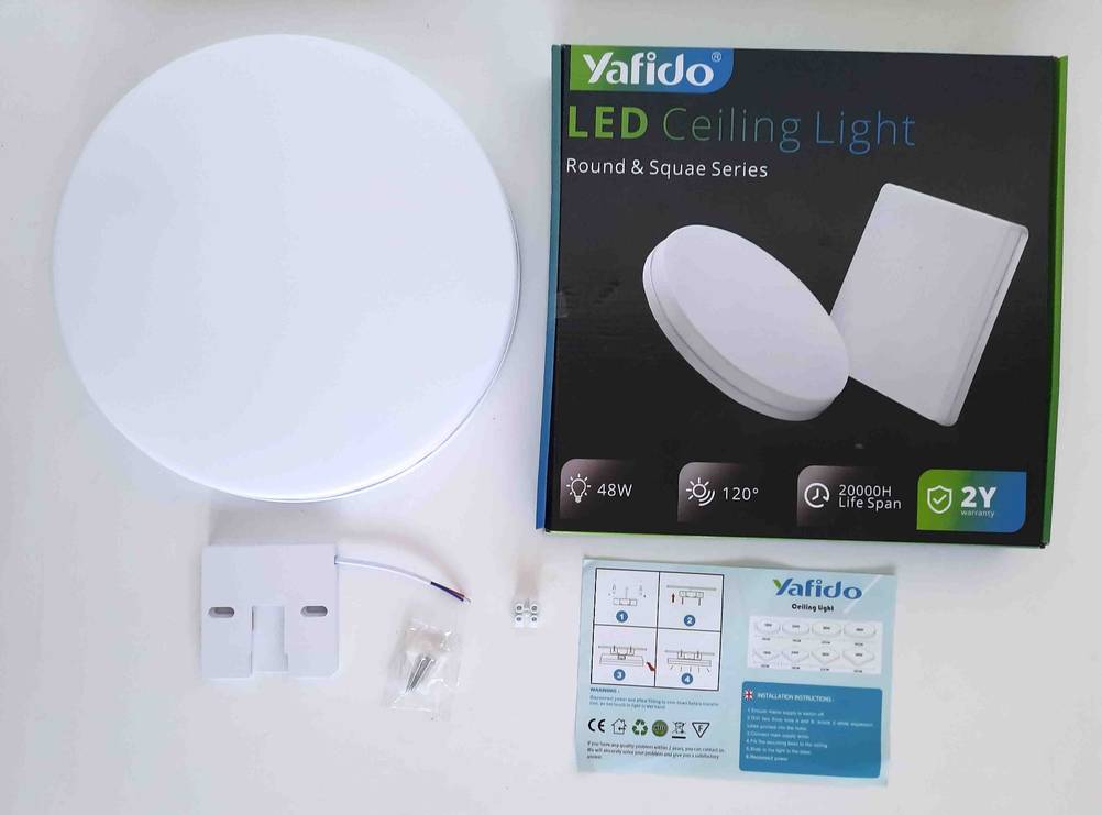 Eine getestete LED-Deckenleuchte neben der Originalverpackung und angeordnetem Zubehör auf einer hellen Fläche.