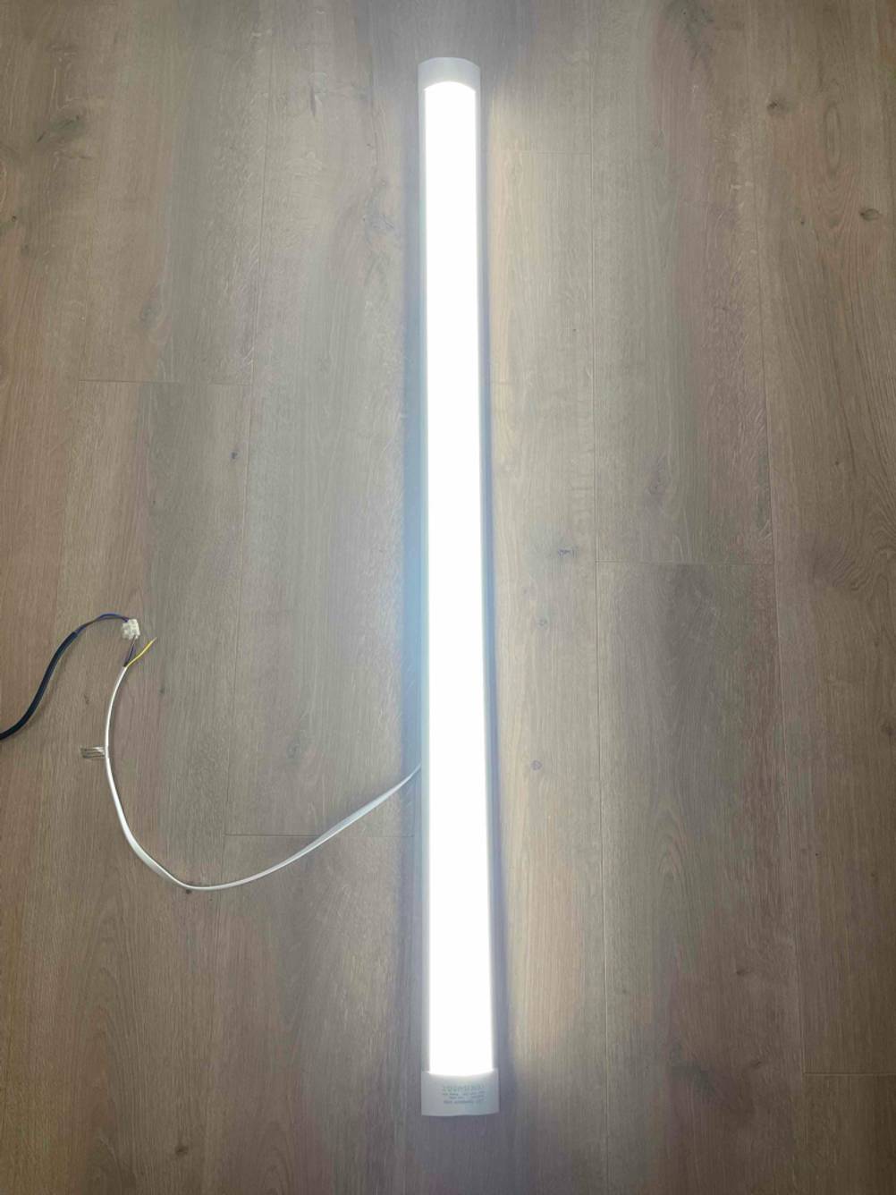 Ein angeschaltener LED-Einbaustrahler im Test liegt auf einer Holzfläche.