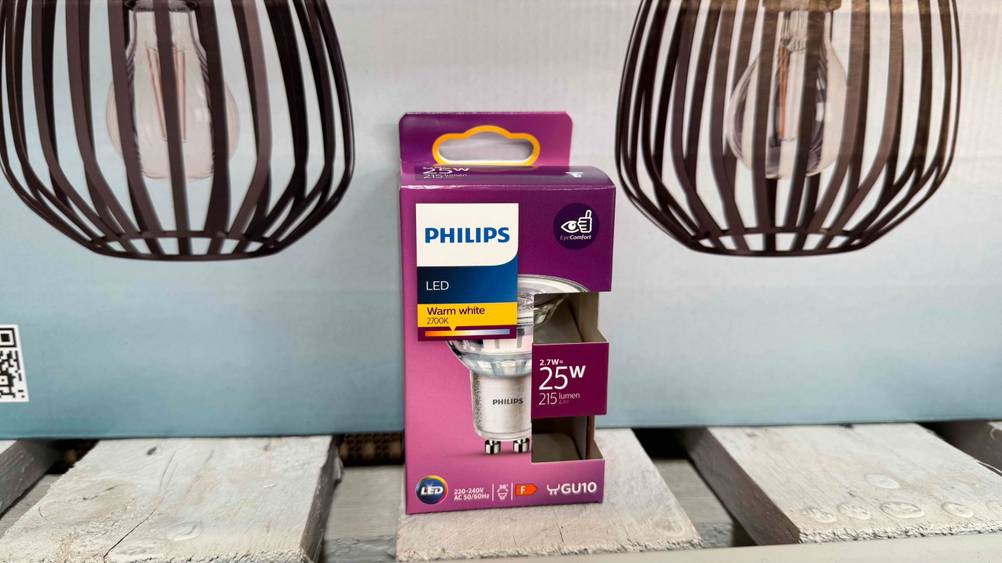 Vor einem Plakat steht eine Packung der getesteten LED-GU10-Warmweiß.
