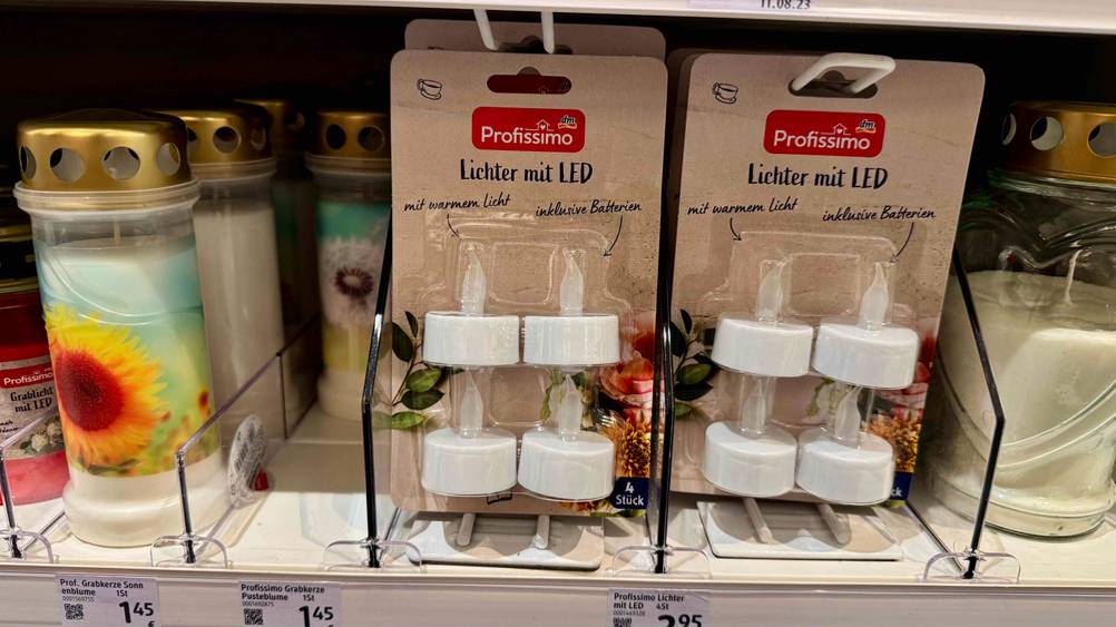 Mehrere Packungen der getesteten LED-Kerzen in einem Verkaufsregal neben anderen Produkten stehend.