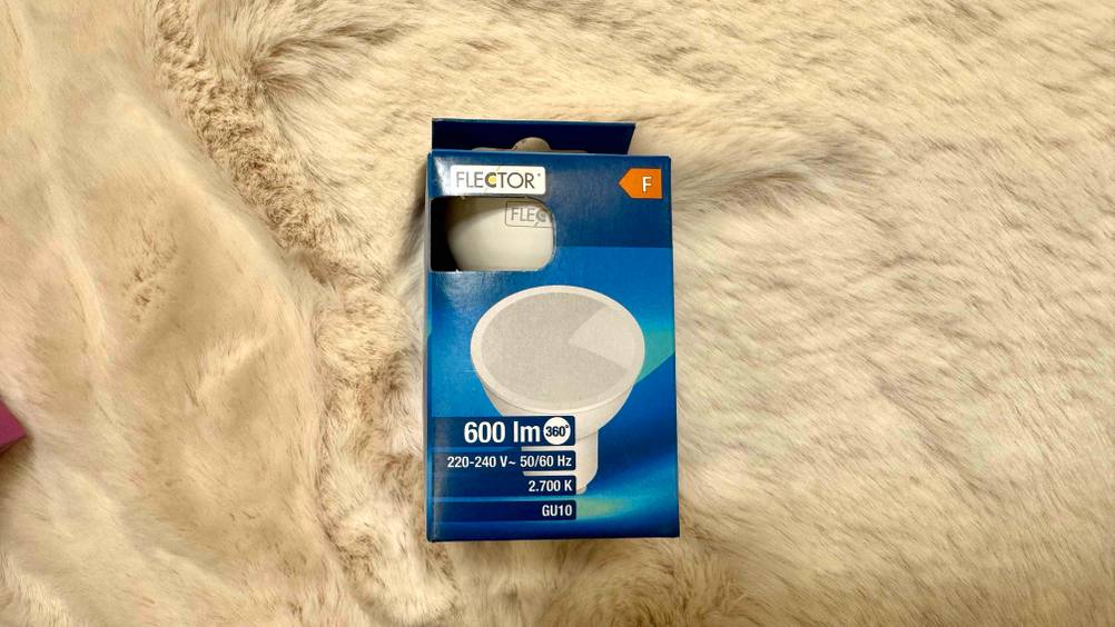 Eine Packung der getesteten LED-Lampen auf einem hellen Fell liegend.