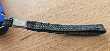 Getestet: Nahaufnahme der Halteschlaufe einer LED-Taschenlampe auf einer Holzfläche.