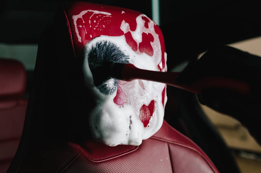 Lederseife-Test: Ein roter Leder-Autositz wird mit einem Pinsel und Lederseife behandelt. 