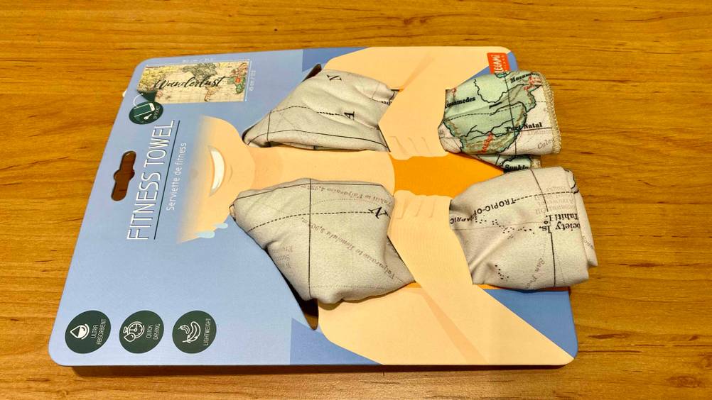 Ein originalverpacktes Sporthandtuch im Test liegt horizontal auf einer Holzfläche.