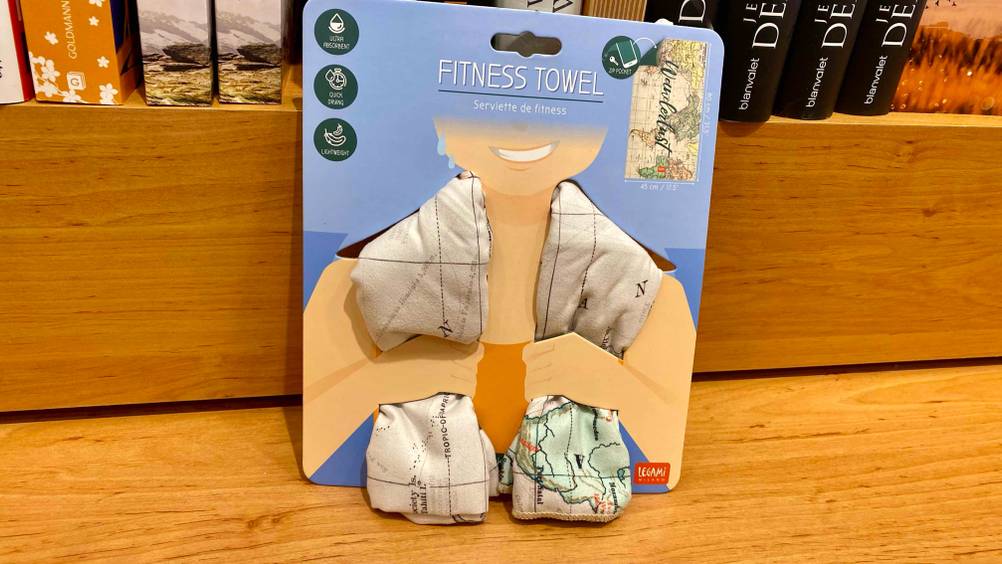 Im Test: Ein originalverpacktes Sporthandtuch lehnt an einem Holzregal.