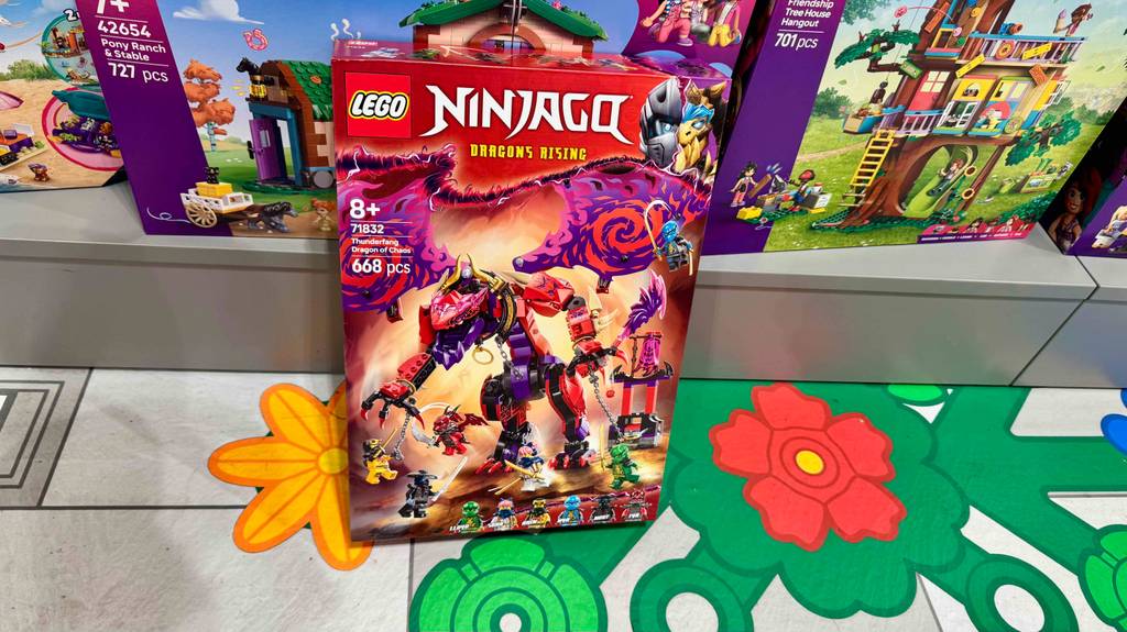 Im Test: Ein Karton mit Lego-Ninjago-Figuren steht auf einem bunten Boden vor anderen Aufbausets.