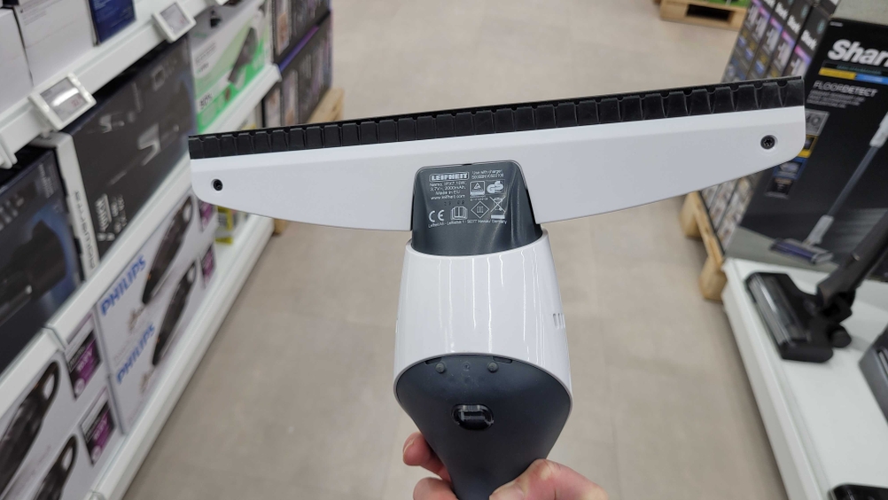 Fenstersauger getestet: Unterseite eines Gerätes von einer Hand gehalten vor einem grauen Hintergrund.