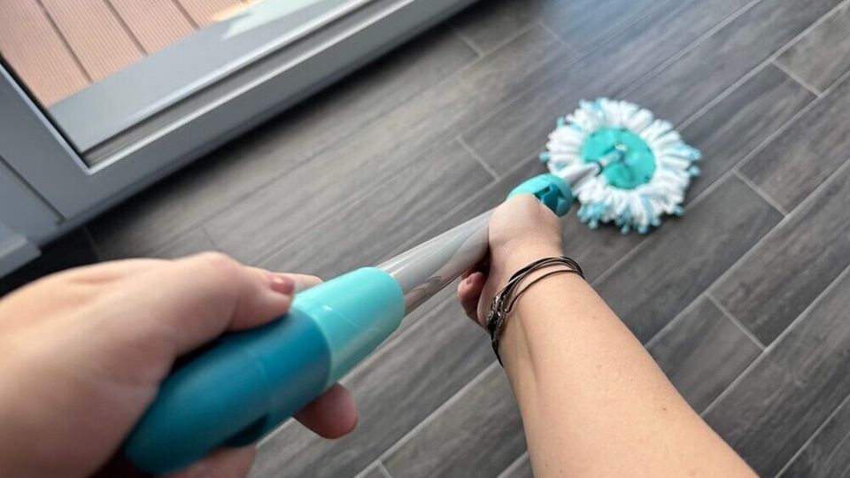 Zwei Hände reinigen Fliesenboden mithilfe des Leifheit 52102