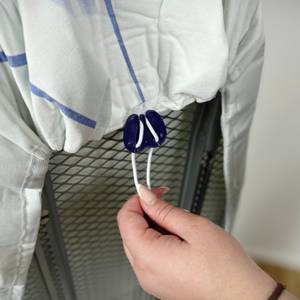 Rückseite eines Bügelbretts mit aufgezogenem Leifheit Thermo Reflect Glide & Park. Die Schnur des Bezugs wird mit einem Stopper fixiert.