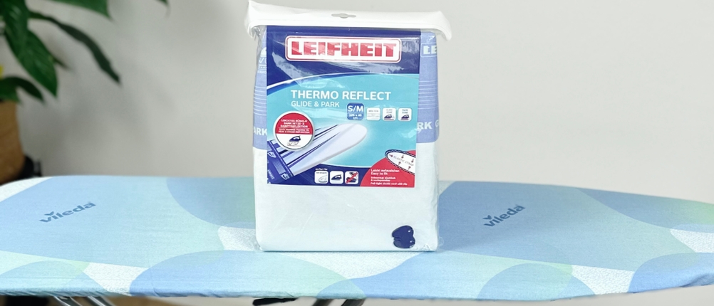 Der Leifheit Bügeltischbezug Thermo Reflect Glide & Park steht verpackt auf einem blauen Bügelbrett.