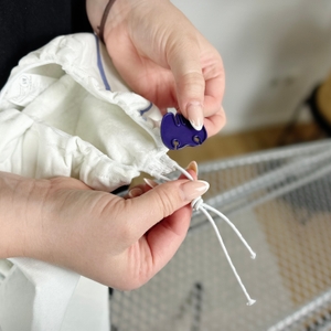 Der Stoppermechanismus des Leifheit Bügeltischbezugs Thermo Reflect Glide & Park wird in einer Hand gehalten.