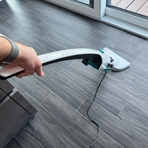 Eine Hand reinigt einen Fliesenboden mithilfe des Leifheit CleanTenso Power 2.0