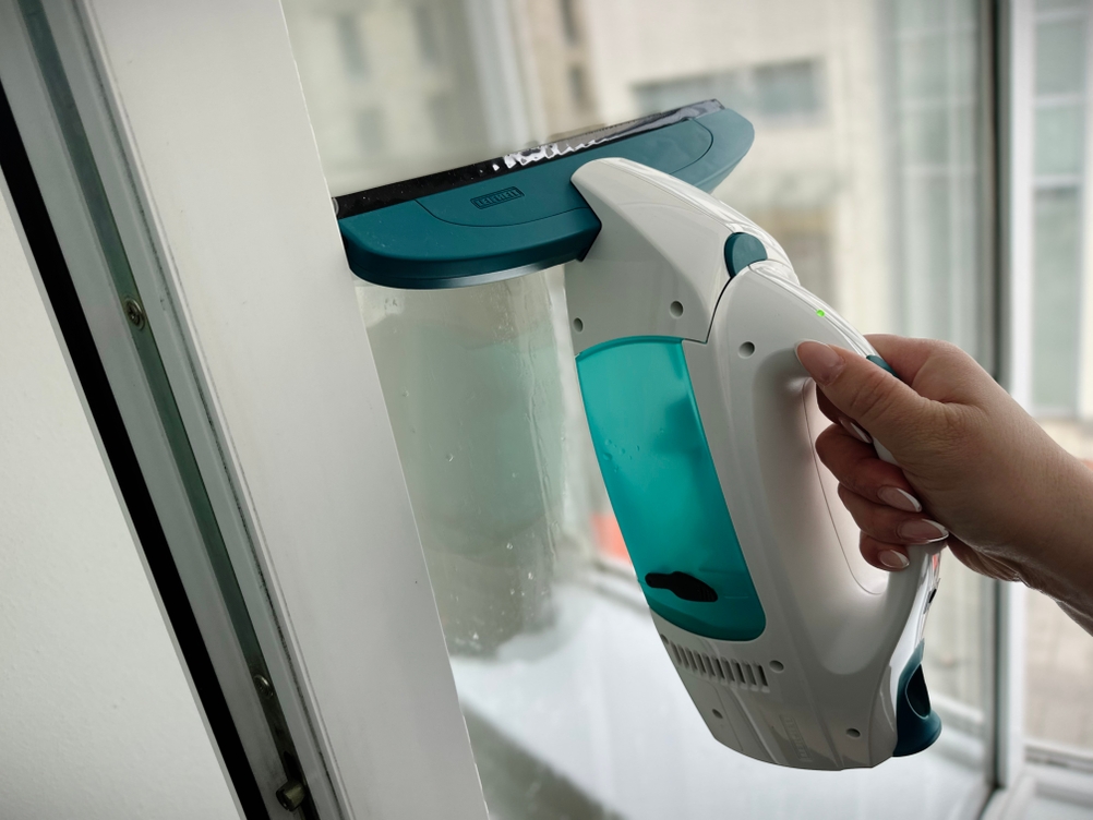 Der Leifheit Dry & Clean wird direkt an einem Fenster geführt. Das Gerät saugt Feuchtigkeit an der Glasfläche ab.