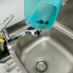 Der Wassertank des Leifheit Dry & Clean wird über einem Spülbecken entleert. Das türkisfarbene Kunststoffgehäuse wird leicht gekippt.