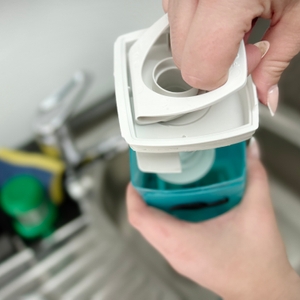 Der Leifheit Dry & Clean wird in zwei Teile zerlegt. Eine Hand hebt den oberen Gerätekopf vom Tankgehäuse ab.