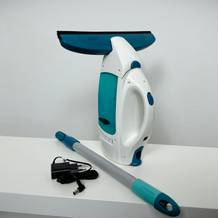 Der Leifheit Dry & Clean steht mit Zubehör auf einem weißen Tisch. Dargestellt sind Ladegerät und Verlängerungsstange.