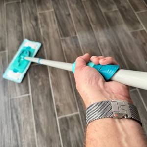 Eine Hand reinigt Fliesenboden mit dem Bodenwischer des Leifheit Set Clean Twist M.