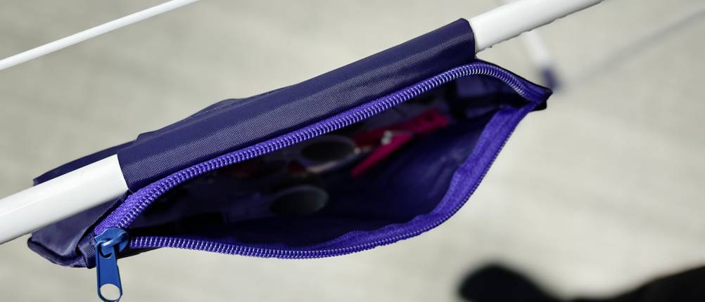Der Stoffbeutel für Wäscheklammern ist mit einem Reißverschluss am Gestell des Leifheit-Standtrockners 81510 befestigt. Im Inneren sind Klammern und Zubehör sichtbar.