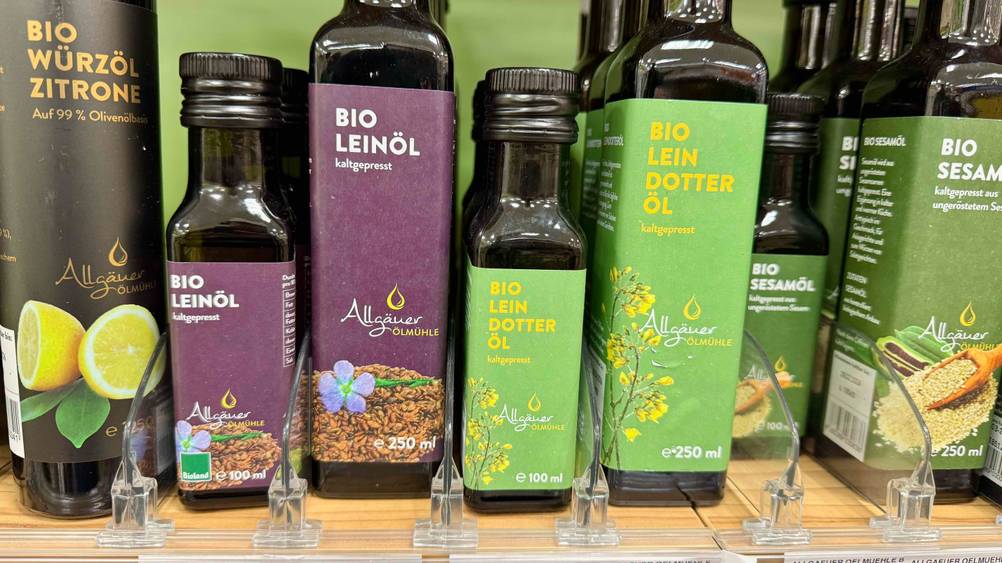 Auf einem Verkaufsregal stehen mehrere Flaschen des getesteten Leindotteröls neben anderen Produkten.