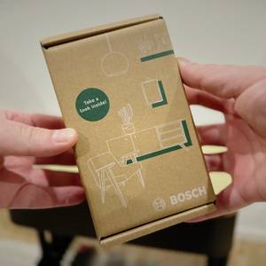 Zwei Hände halten die Verpackung des Leitungssuchers von Bosch.