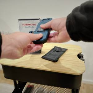 Eine Person schließt das Batterienfach des Leitungssuchers von Hanmatek.