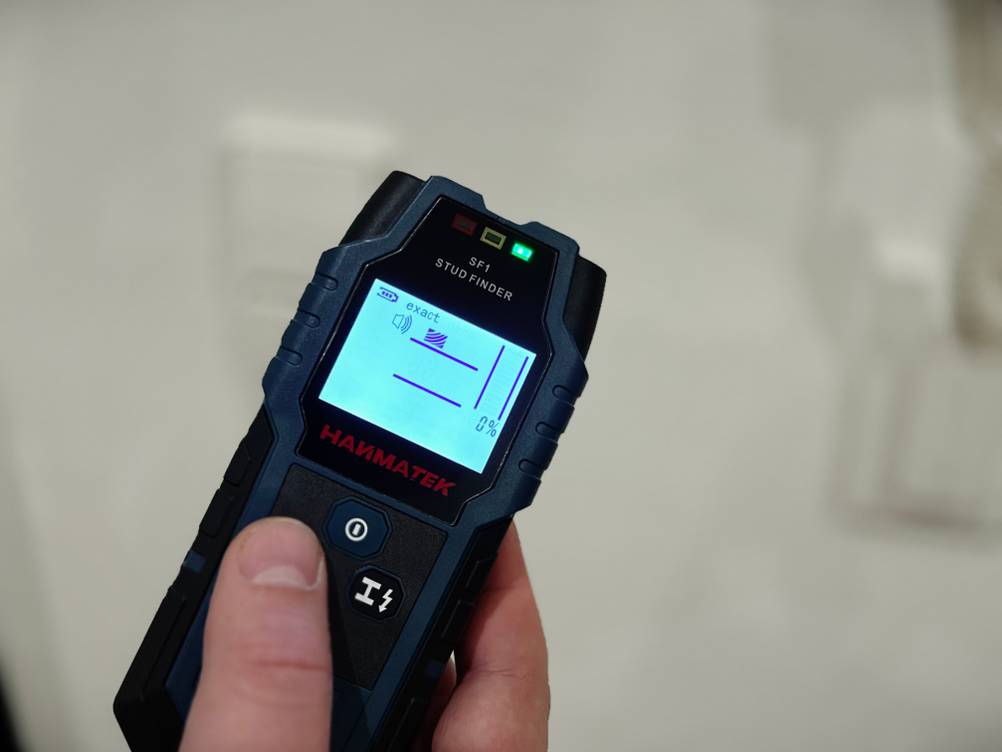 Eine Hand hält den eingeschalteten Leitungssucher von Hanmatek.