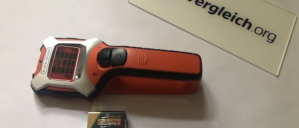 Ein Leitungssucher von Black+Decker liegt mit dem Akku auf dem Boden.
