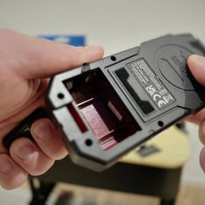 Eine Hand hält den Leitungssucher von Testboy mit einem offenen Batteriefach.