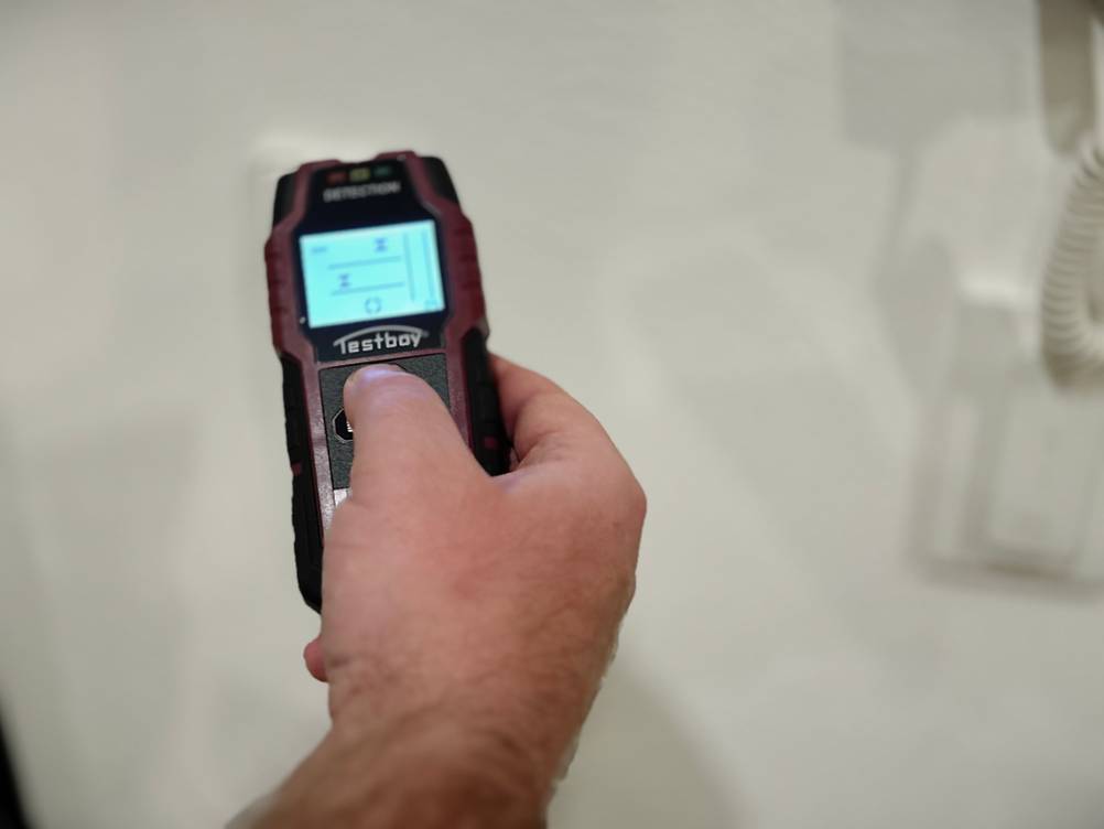 Eine Hand hält den eingeschalteten Leitungssucher von Testboy.