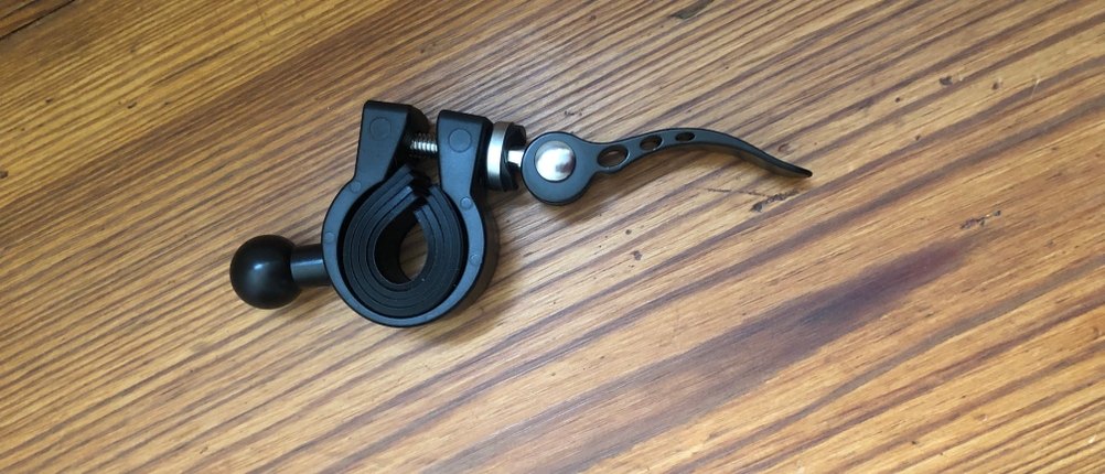 Drehgelenk einer Fahrrad-Handyhalterung liegt auf einem Holzboden.